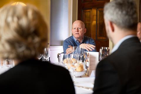 Photograph focused on DWF partner Paul Holmes, taken from across the table behind the backs of two attendees. A bowl of bread rolls sits in the centre of the table among wine glasses.